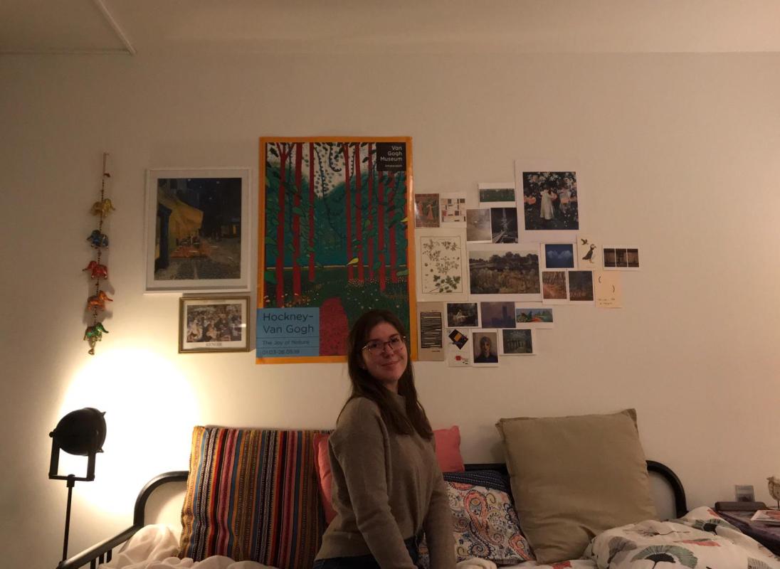Foto van mij voor mijn muur met kaartjes en posters van kunstwerken